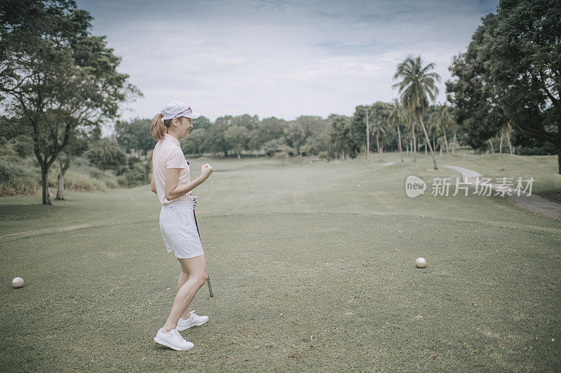 asian chinese female golfer teeing off at golf course rear view